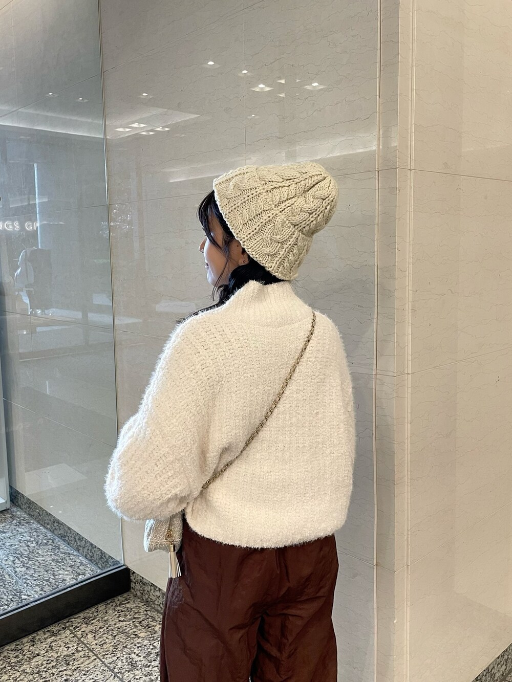 ホワイト系のニット/セーター、ブラウン系のその他パンツ、ベージュ系のショルダーバッグを着用したレディースの秋コーディネートの6枚目の写真