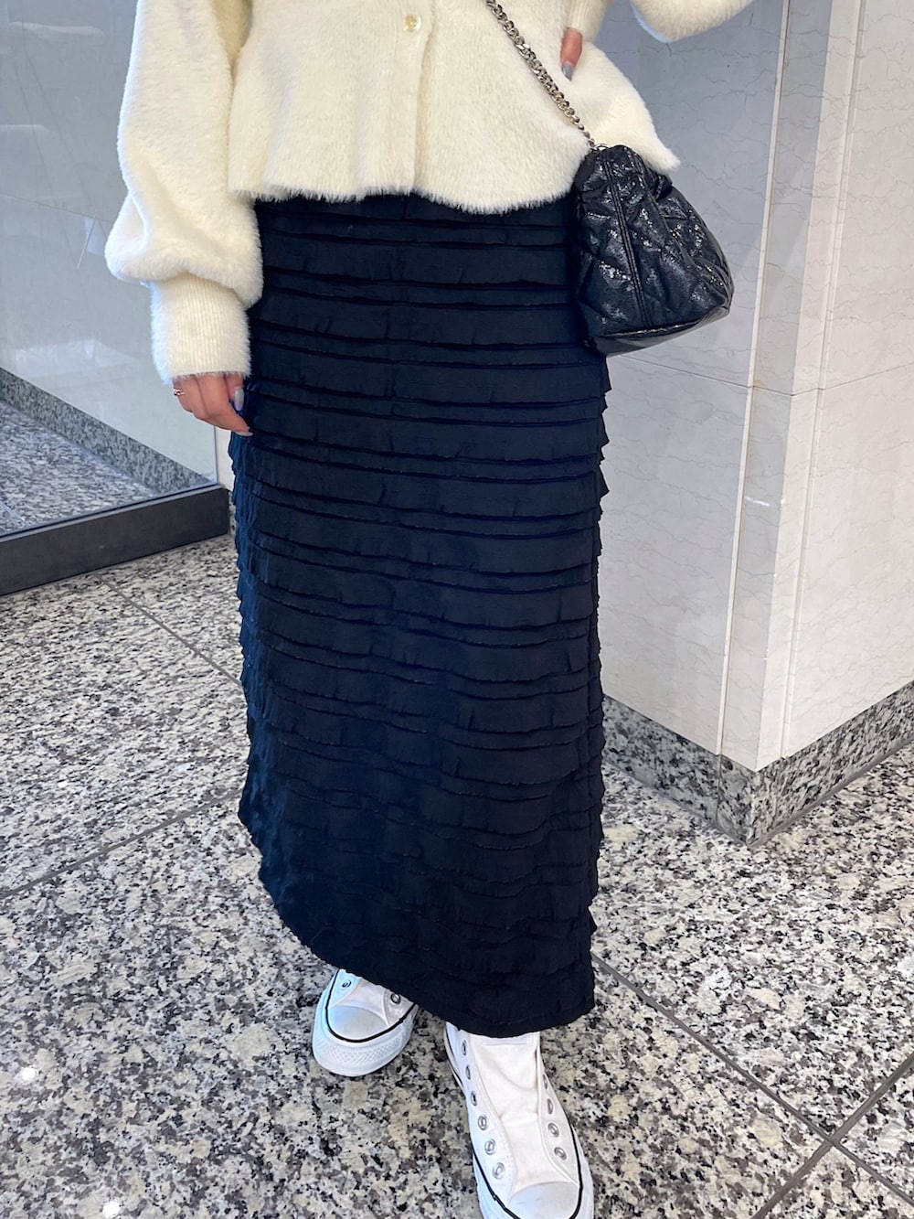 ホワイト系のカーディガン/ボレロ、ブラック系のスカート、ブラック系のショルダーバッグを着用したレディースの冬コーディネートの8枚目の写真