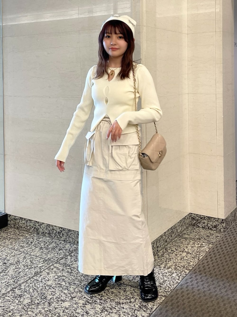 ベージュ系のトレンチコート、ホワイト系のニット/セーター、ベージュ系のショルダーバッグを着用したレディースの春コーディネートの6枚目の写真