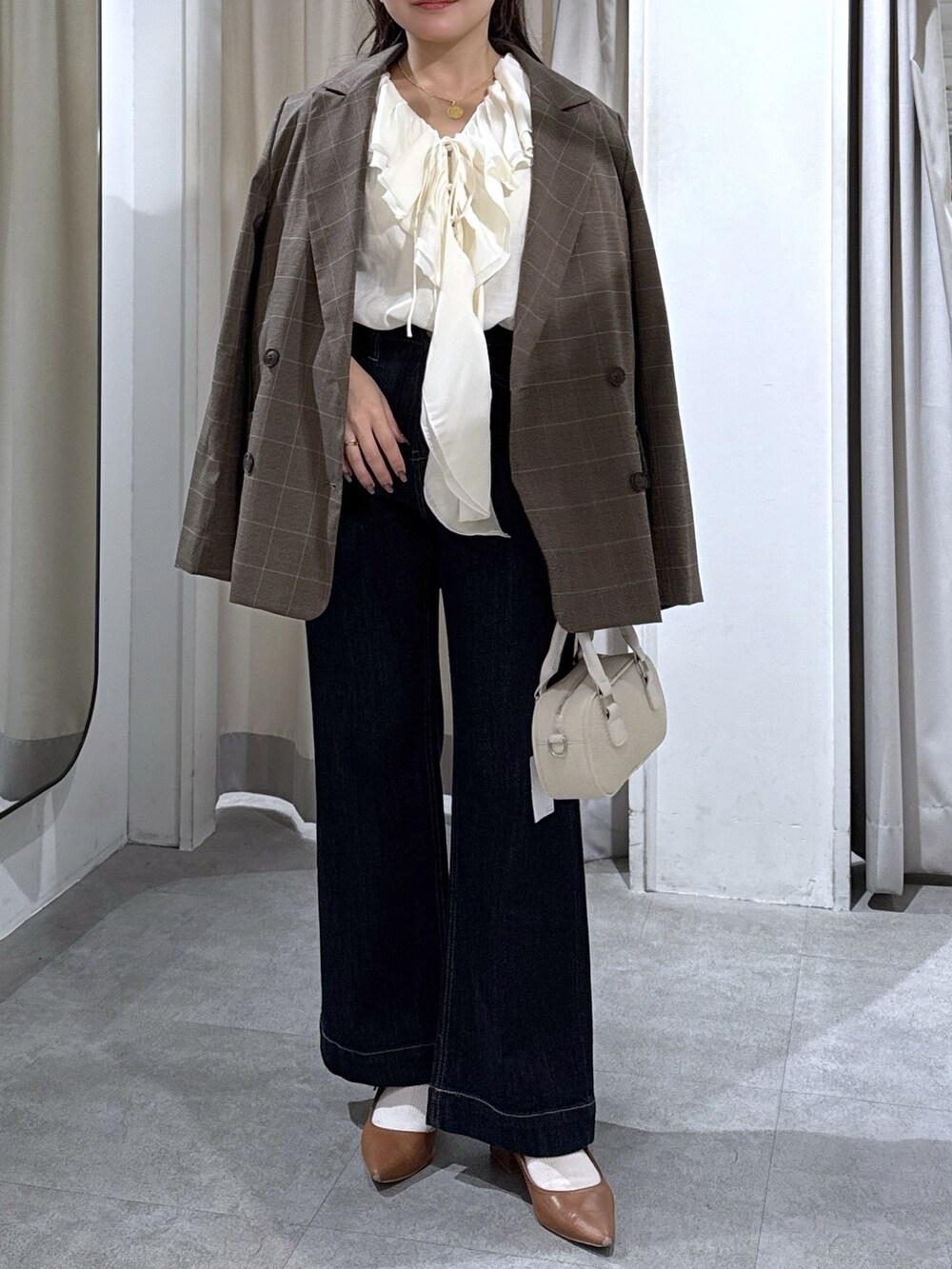 ブラウン系のテーラードジャケット、ホワイト系のシャツ/ブラウス、ブルー系のデニムパンツを着用したレディースの秋コーディネートの4枚目の写真