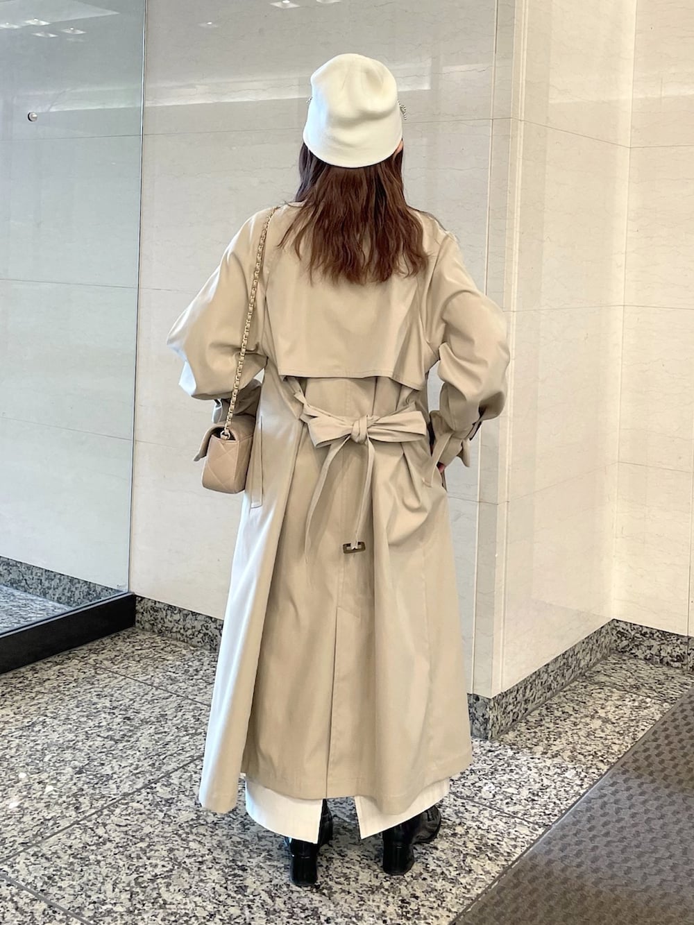 ベージュ系のトレンチコート、ホワイト系のニット/セーター、ベージュ系のショルダーバッグを着用したレディースの春コーディネートの3枚目の写真