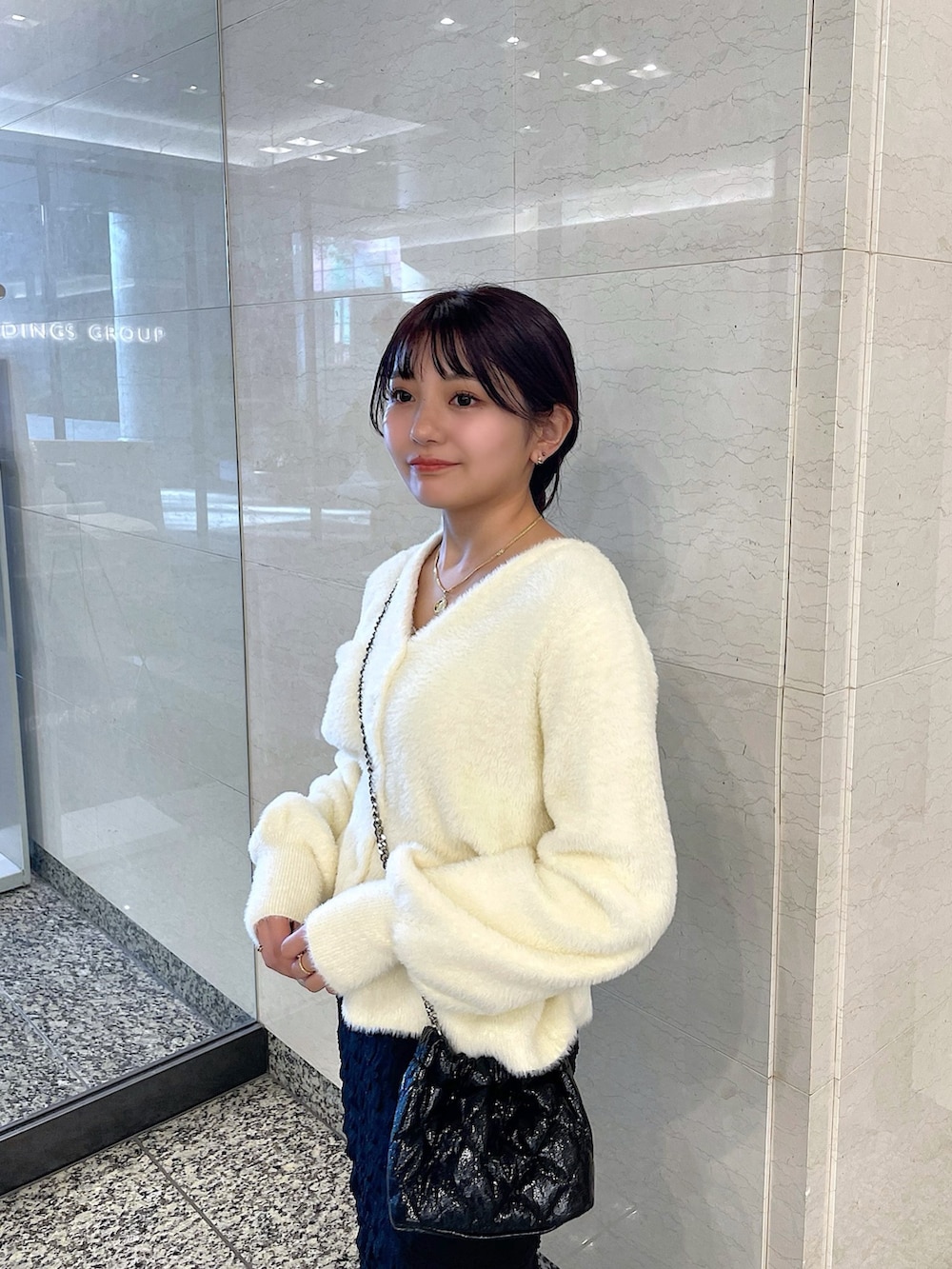 ホワイト系のカーディガン/ボレロ、ブラック系のスカート、ブラック系のショルダーバッグを着用したレディースの冬コーディネートの5枚目の写真