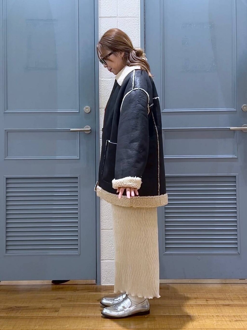 ブラック系のブルゾン、ホワイト系のスカート、シルバー系のローファーを着用したレディースの冬コーディネートの3枚目の写真