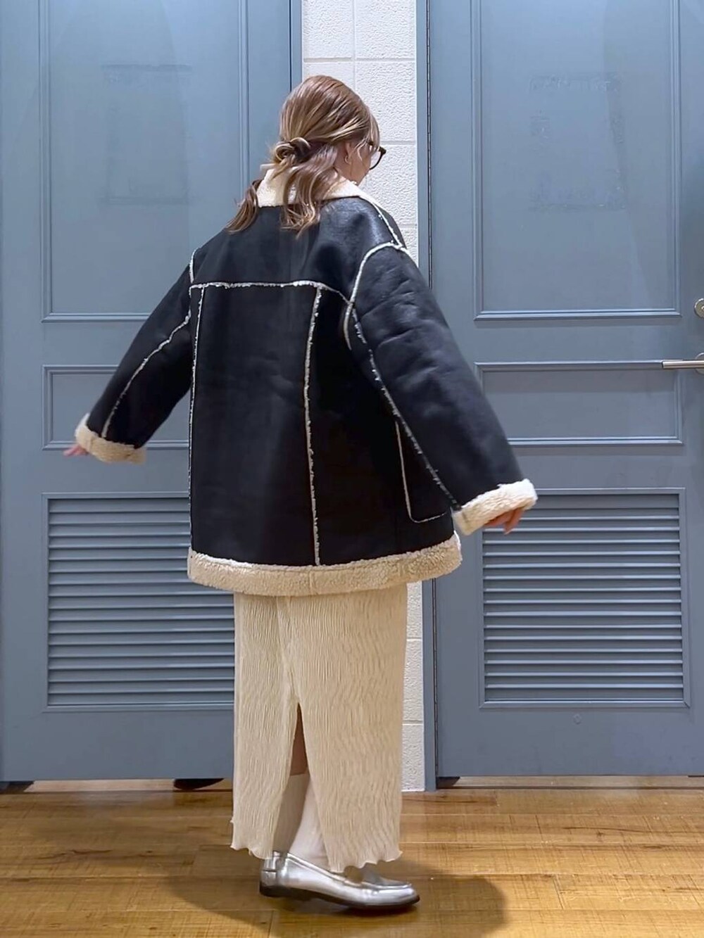 ブラック系のブルゾン、ホワイト系のスカート、シルバー系のローファーを着用したレディースの冬コーディネートの2枚目の写真