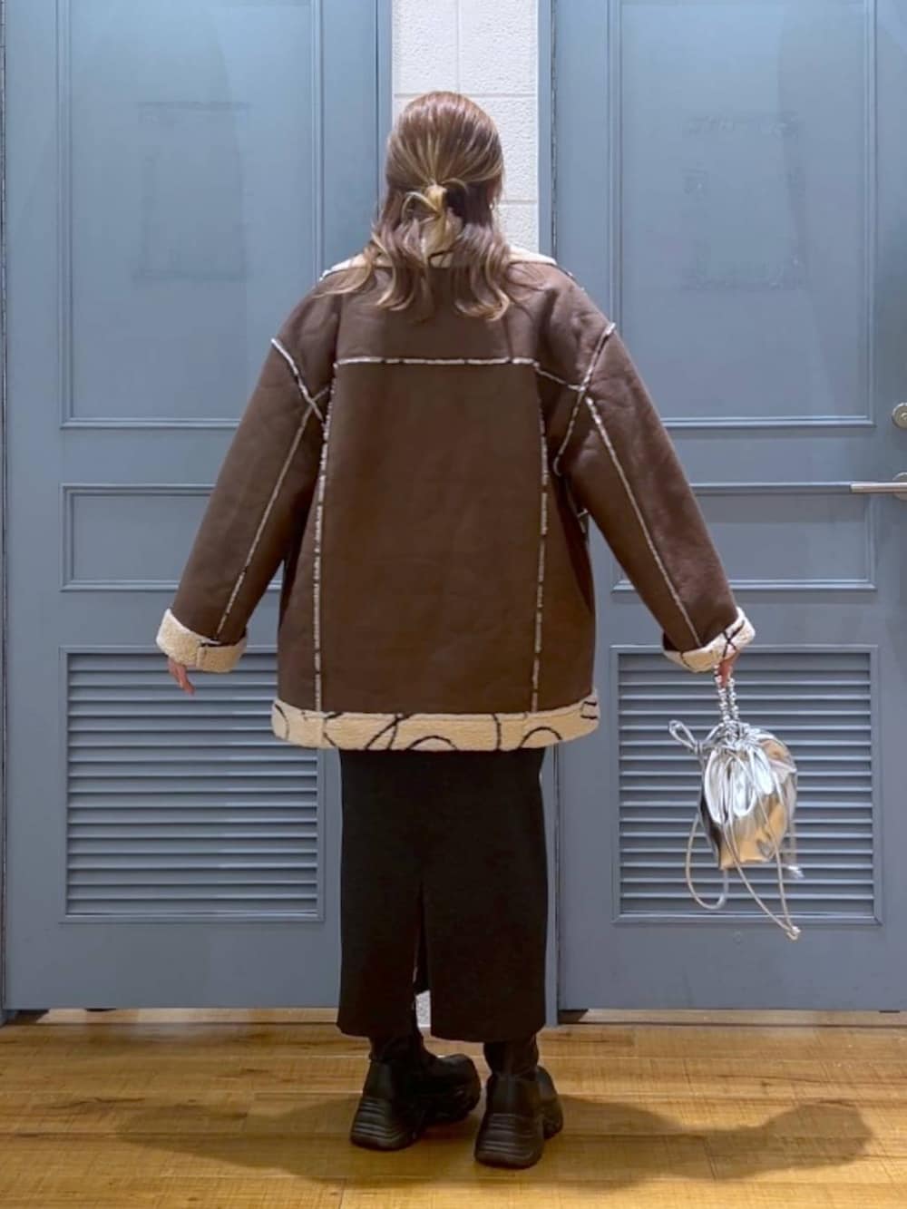 ブラウン系のブルゾン、レッド系のニット/セーター、シルバー系のショルダーバッグを着用したレディースの冬コーディネートの4枚目の写真