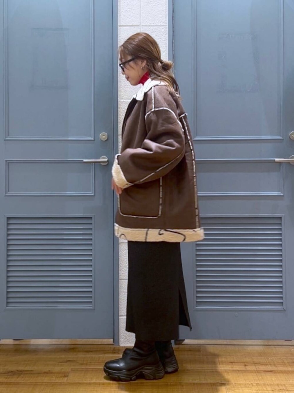 ブラウン系のブルゾン、レッド系のニット/セーター、シルバー系のショルダーバッグを着用したレディースの冬コーディネートの3枚目の写真