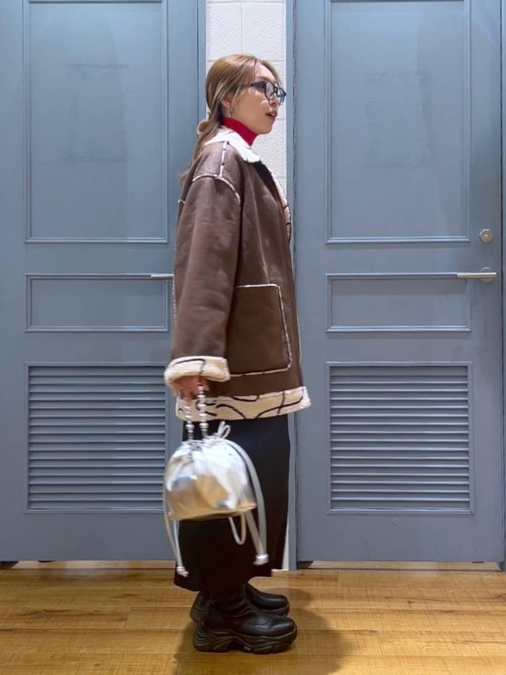 ブラウン系のブルゾン、レッド系のニット/セーター、シルバー系のショルダーバッグを着用したレディースの冬コーディネートの2枚目の写真