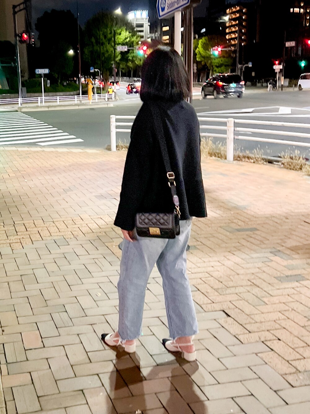 ブラック系のニット/セーター、ブラック系のボディバッグ/ウエストポーチ、ブルー系のデニムパンツを着用したレディースの秋コーディネートの2枚目の写真