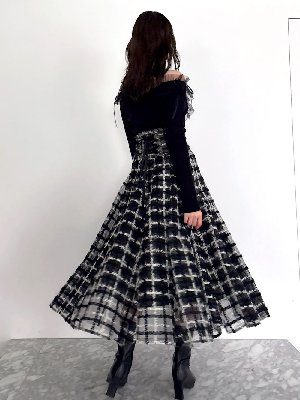 ブラック系のニット/セーター、ブラック系のスカート、ブラック系のブーツを着用したレディースの秋コーディネートの8枚目の写真