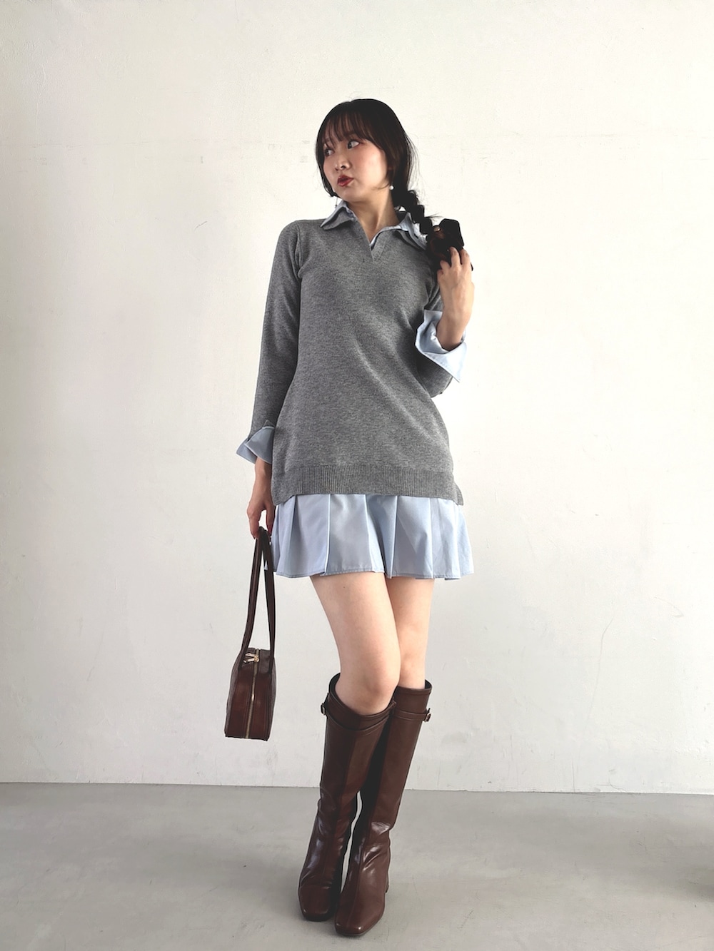 グレー系のワンピース、ブラウン系のハンドバッグ、ブラウン系のブーツを着用したレディースの秋コーディネートの2枚目の写真