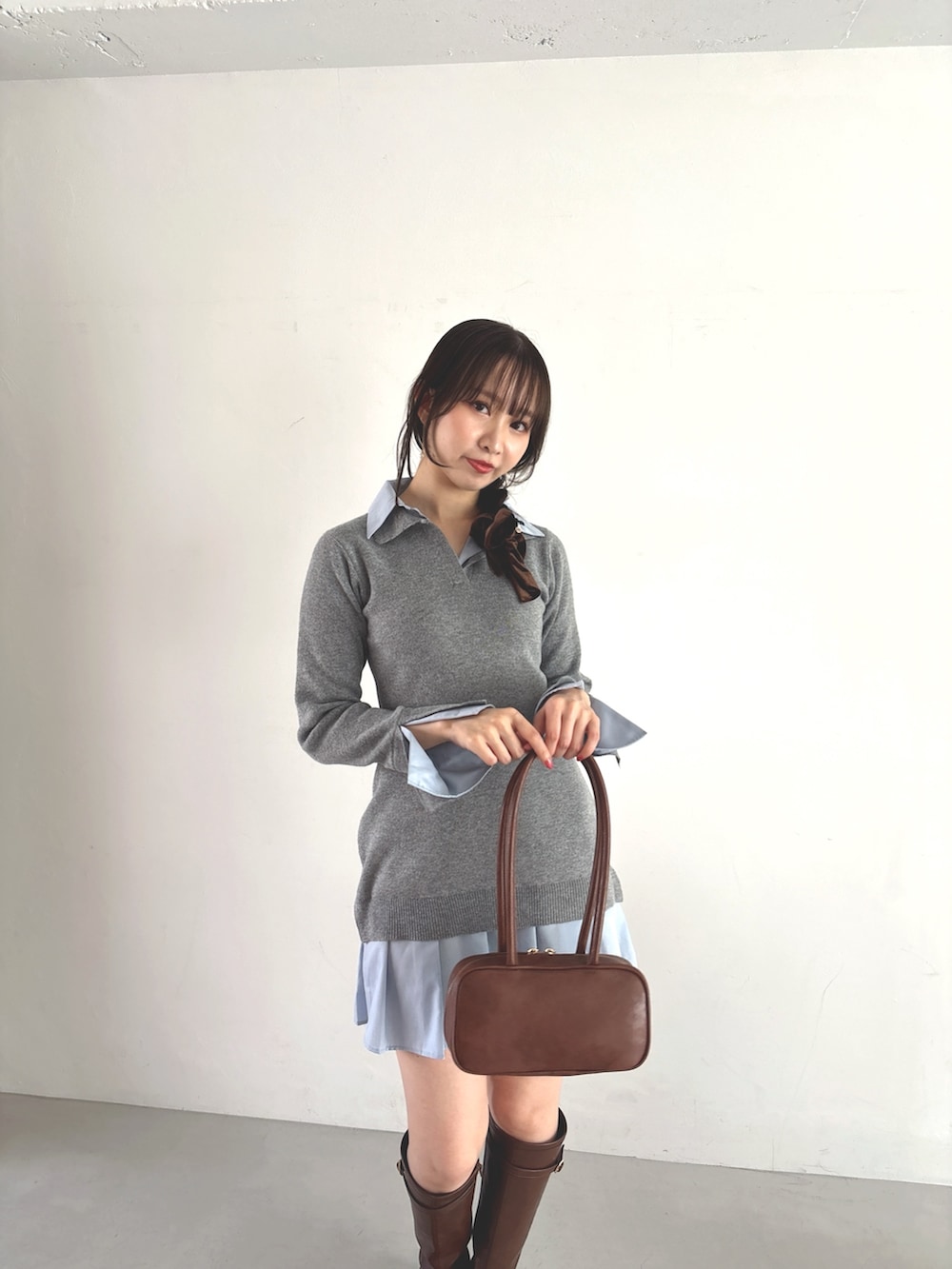 グレー系のワンピース、ブラウン系のハンドバッグ、ブラウン系のブーツを着用したレディースの秋コーディネートの5枚目の写真