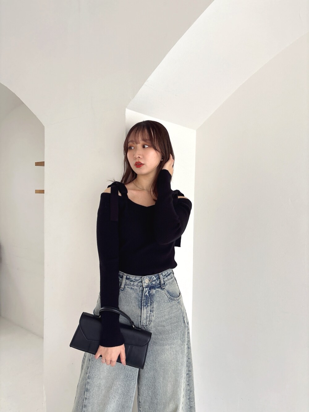 ブラック系のニット/セーター、ブルー系のデニムパンツを着用したレディースの冬コーディネートの4枚目の写真