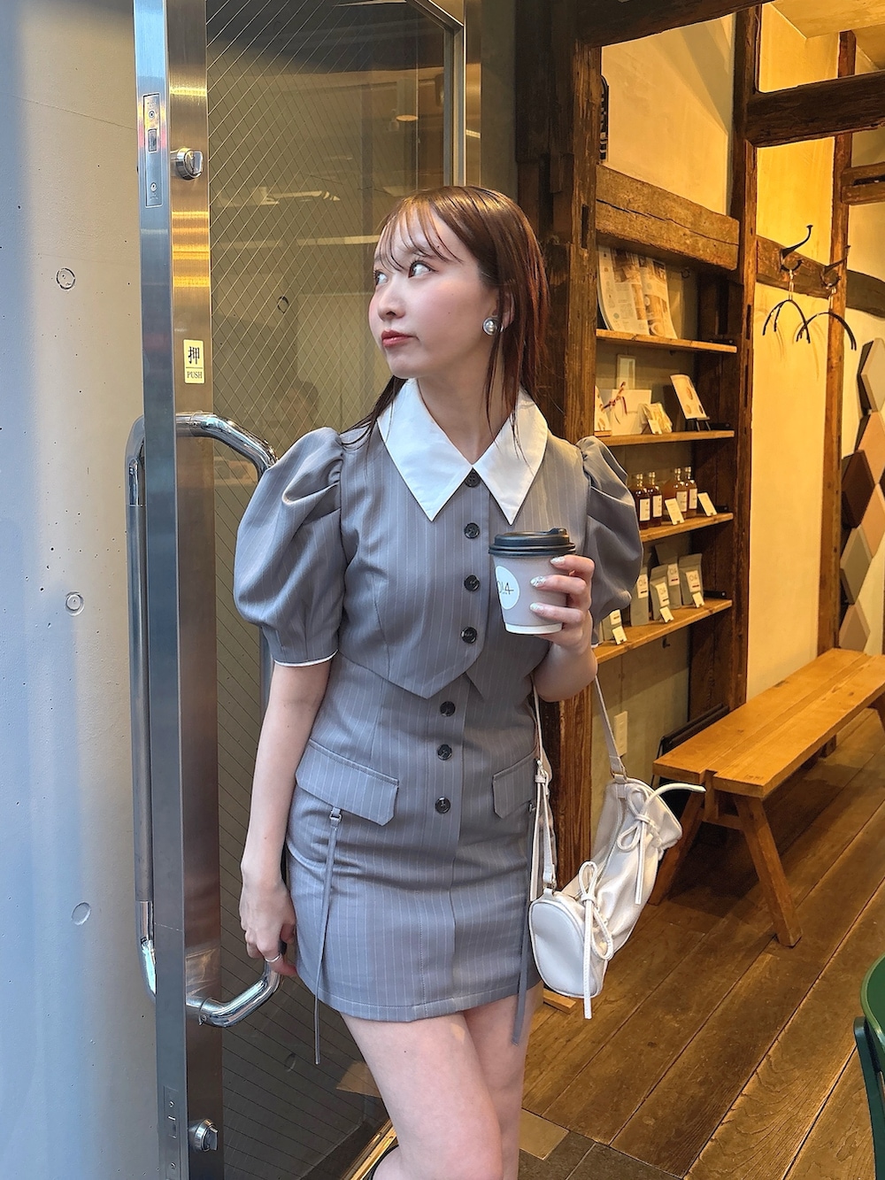 グレー系のワンピース、ホワイト系のハンドバッグを着用したレディースの春コーディネートの2枚目の写真