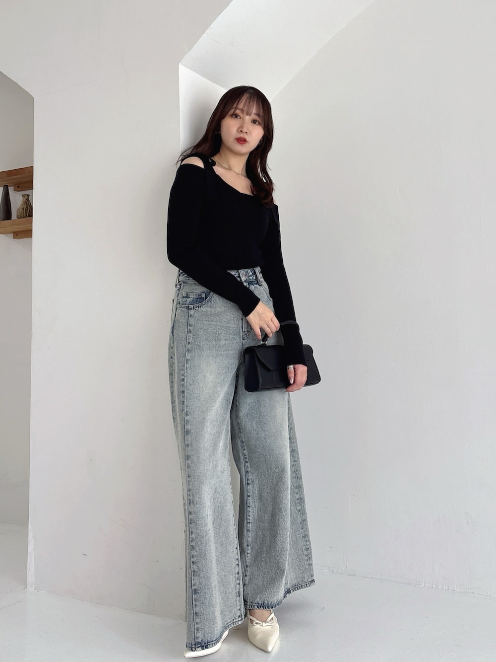 ブラック系のニット/セーター、ブルー系のデニムパンツを着用したレディースの冬コーディネートの6枚目の写真