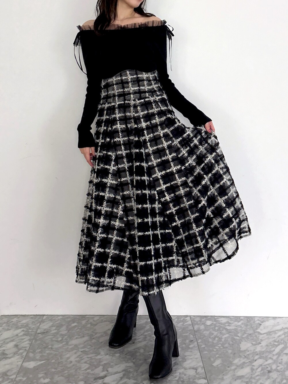 ブラック系のニット/セーター、ブラック系のスカート、ブラック系のブーツを着用したレディースの秋コーディネートの4枚目の写真