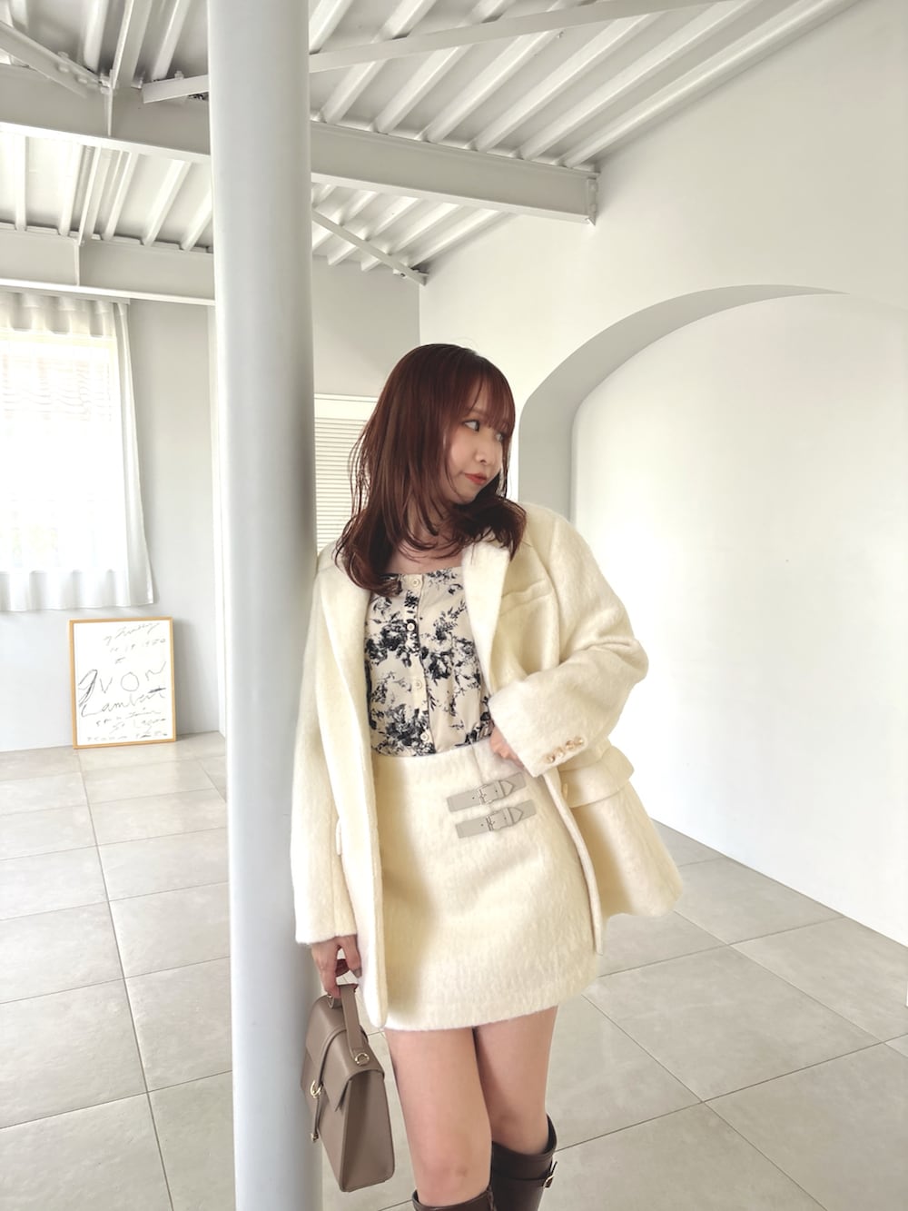 ホワイト系のテーラードジャケット、ホワイト系のスカート、ブラウン系のブーツを着用したレディースの夏コーディネートの7枚目の写真