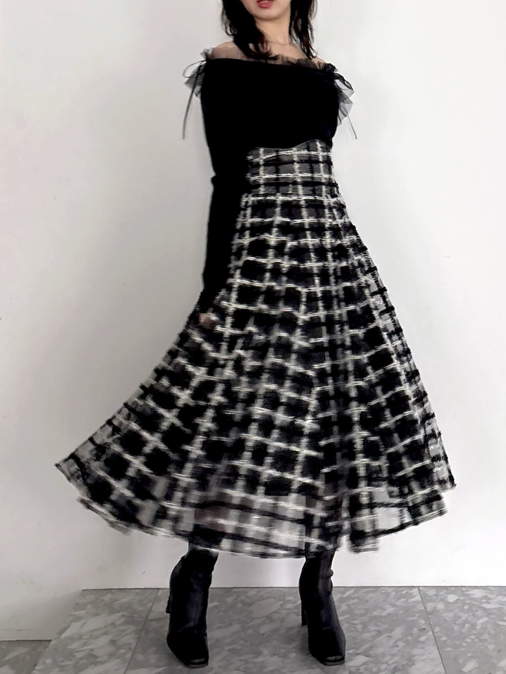 ブラック系のニット/セーター、ブラック系のスカート、ブラック系のブーツを着用したレディースの秋コーディネートの3枚目の写真