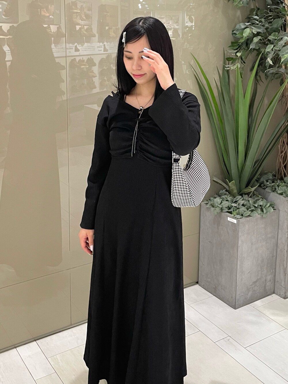 ブラック系のワンピース、ホワイト系のスニーカー、ブラック系のショルダーバッグを着用したレディースの春コーディネートの2枚目の写真