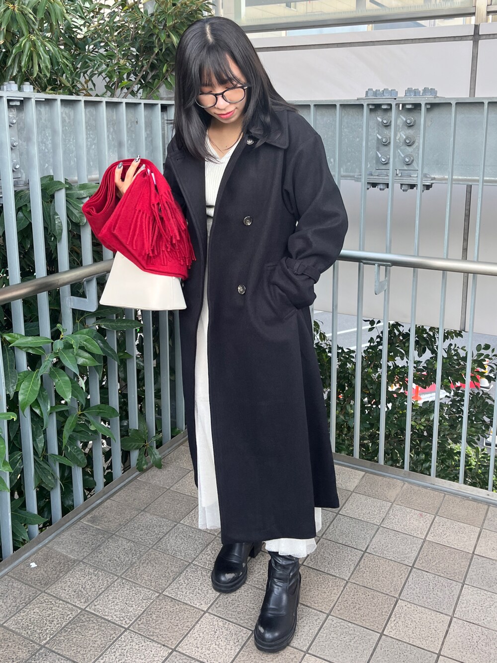 ブラック系のステンカラーコート、ホワイト系のハンドバッグ、レッド系のファッション雑貨を着用したレディースの秋コーディネートの4枚目の写真