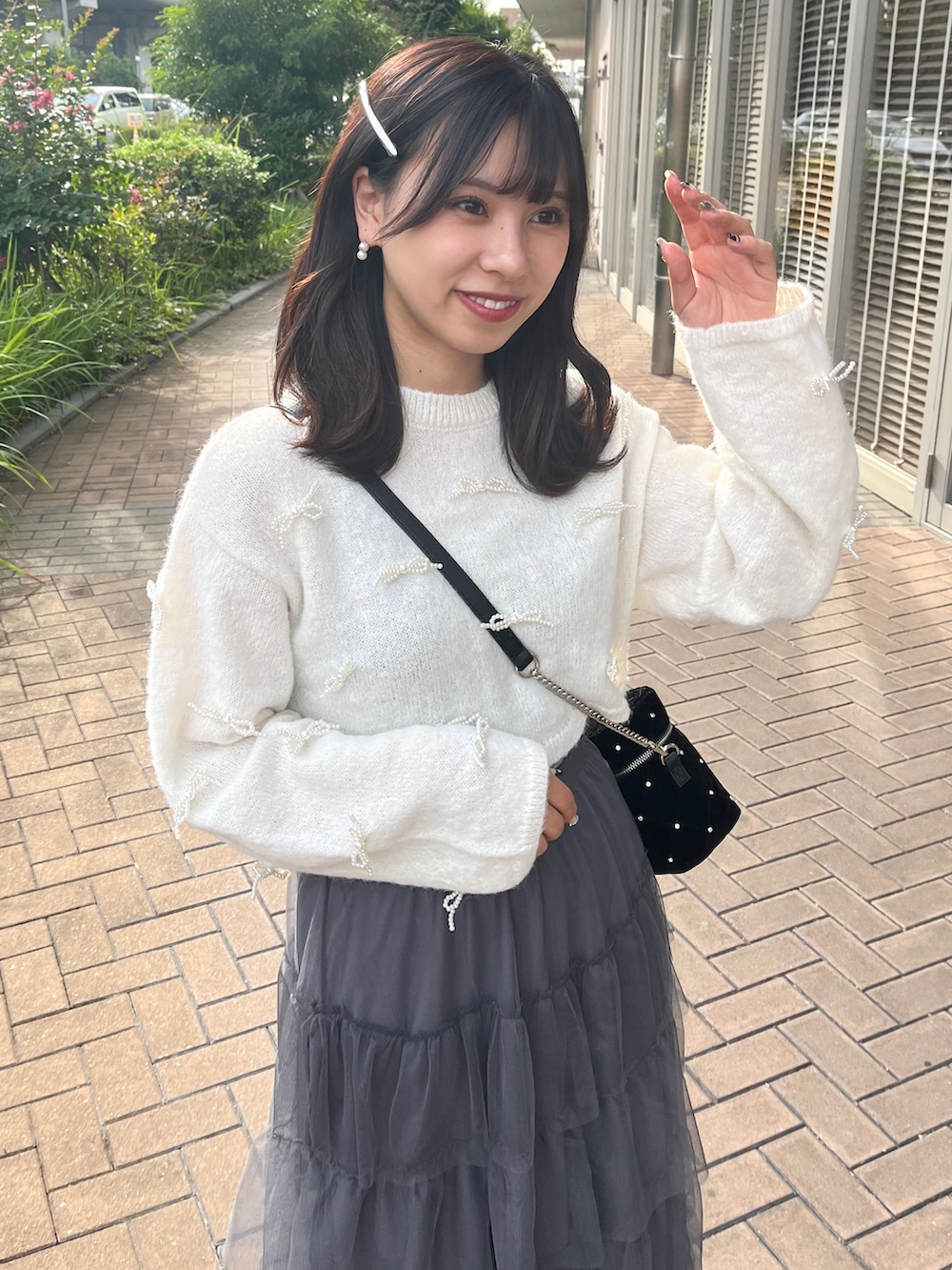 グレー系のスカート、ブラック系のショルダーバッグ、ホワイト系のニット/セーターを着用したレディースの秋コーディネートの2枚目の写真