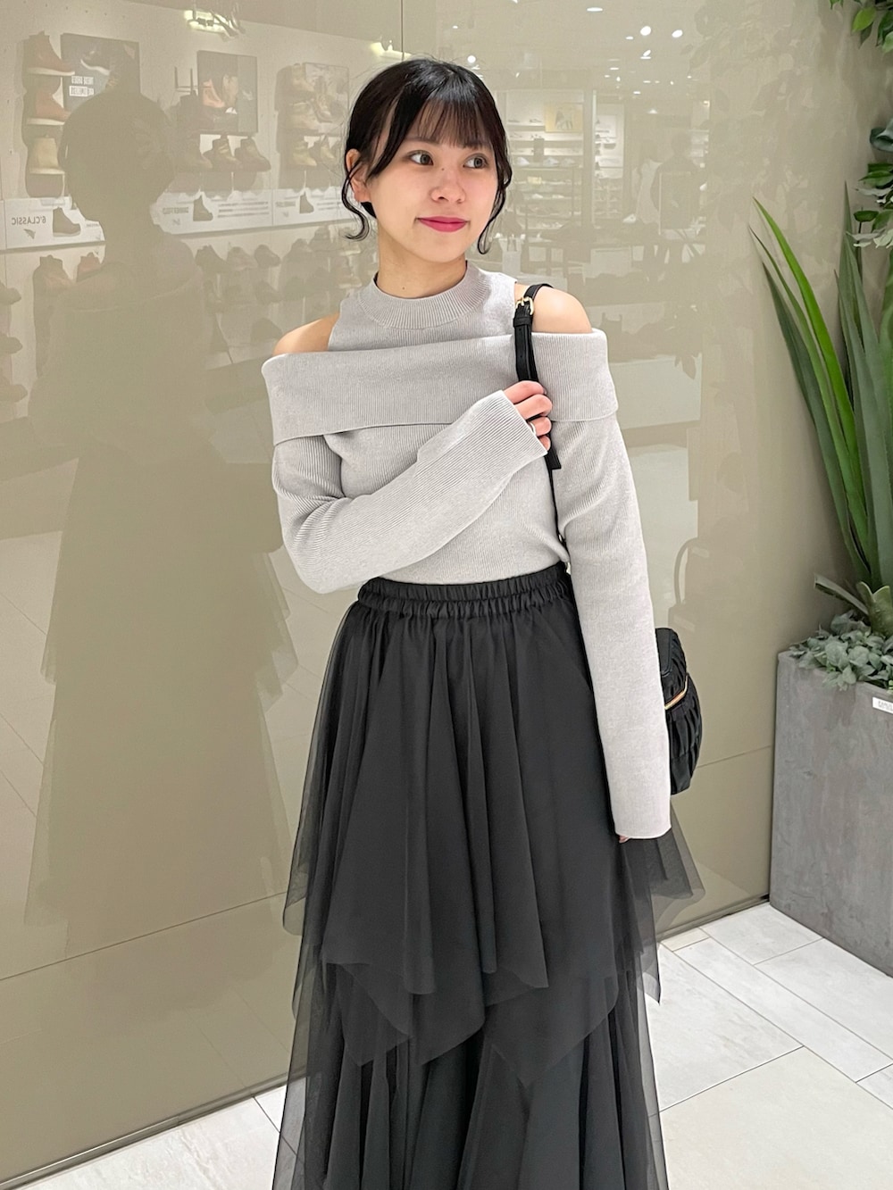 グレー系のニット/セーター、グレー系のスカート、ブラック系のブーツを着用したレディースの春コーディネートの2枚目の写真