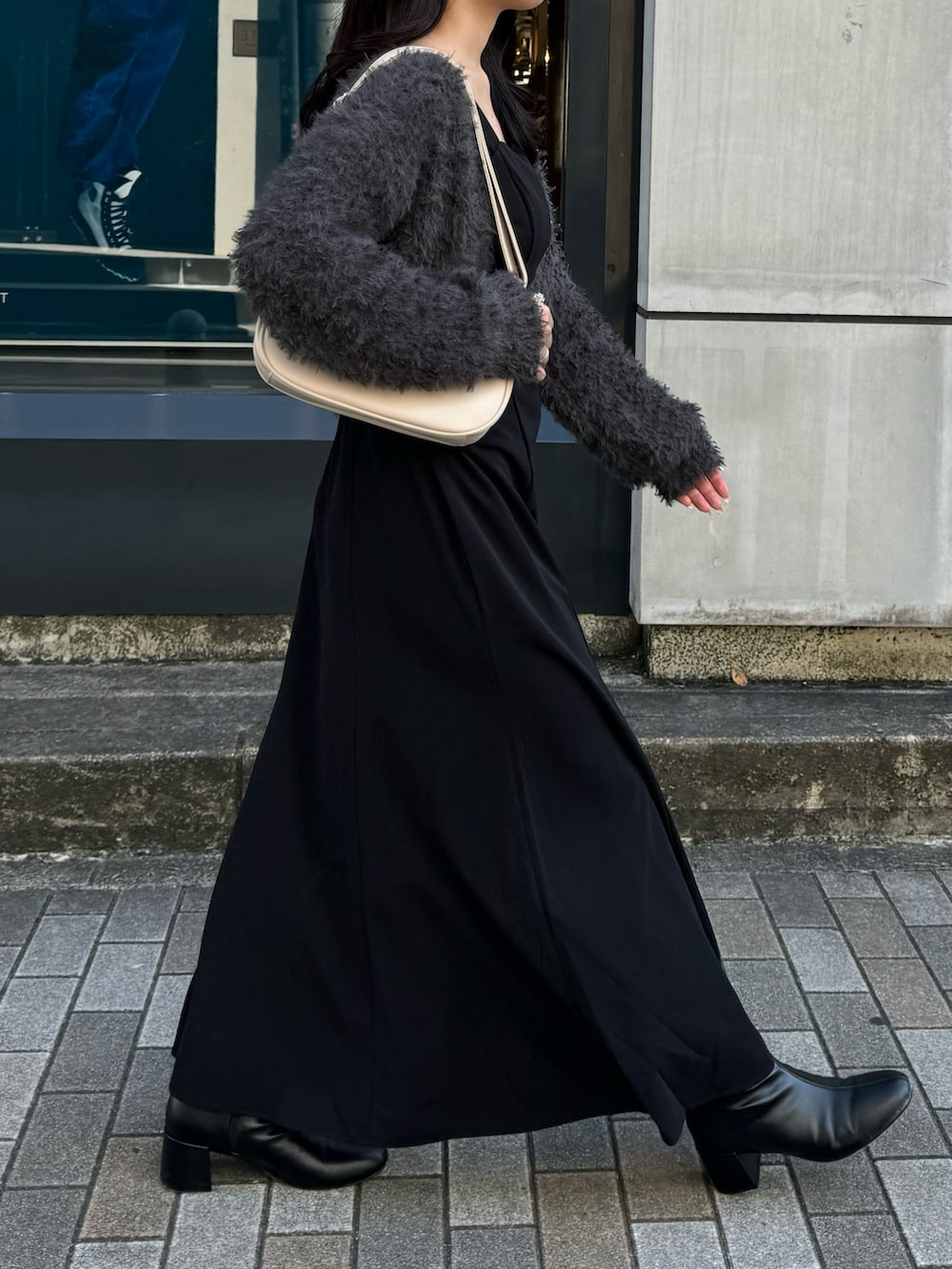 ブラック系のワンピース、グレー系のカーディガン/ボレロ、ブラック系のブーツを着用したレディースの秋コーディネートの3枚目の写真