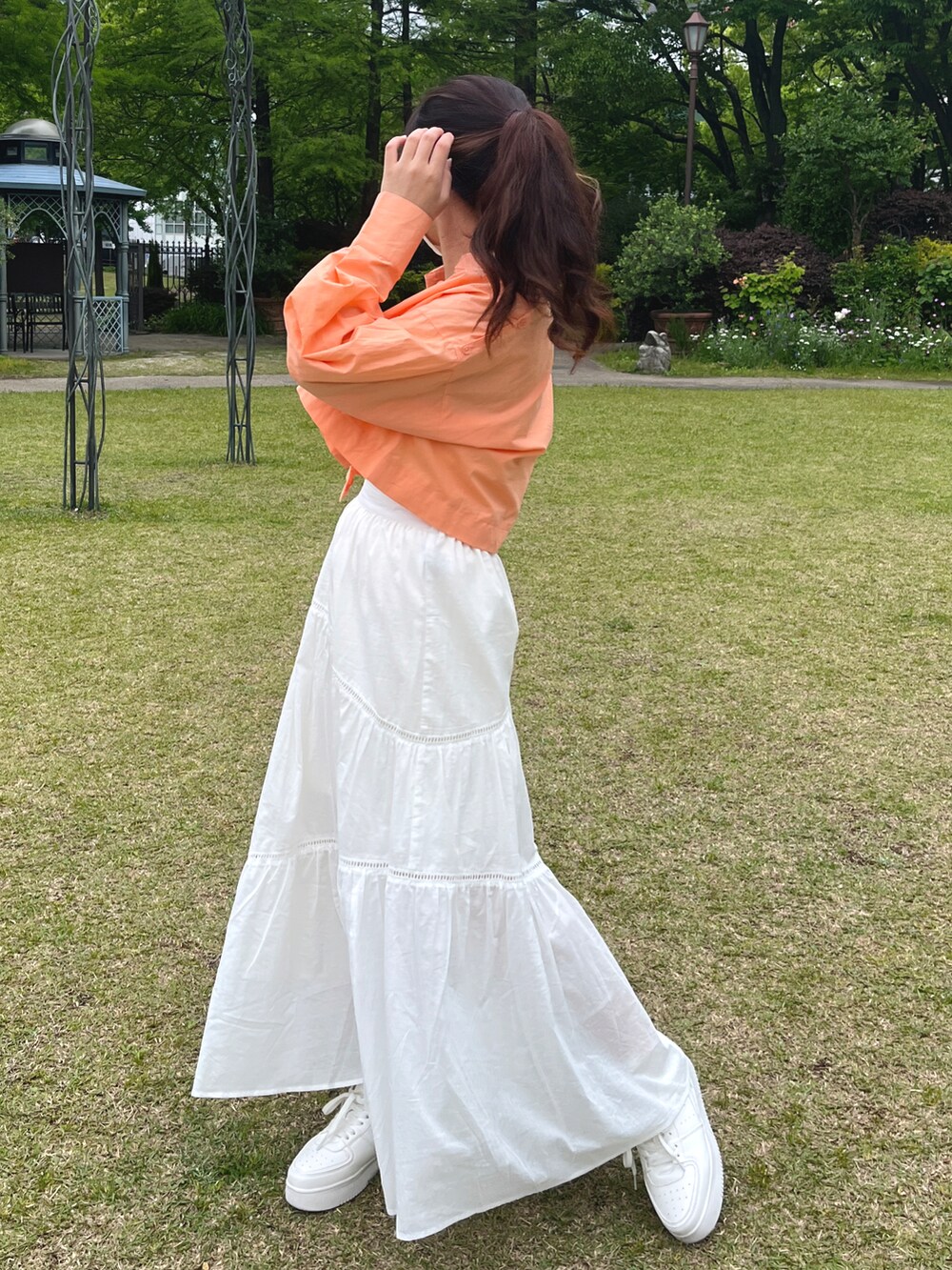 オレンジ系のシャツ/ブラウス、ホワイト系のキャミソール、ホワイト系のスカートを着用したレディースの春コーディネートの2枚目の写真
