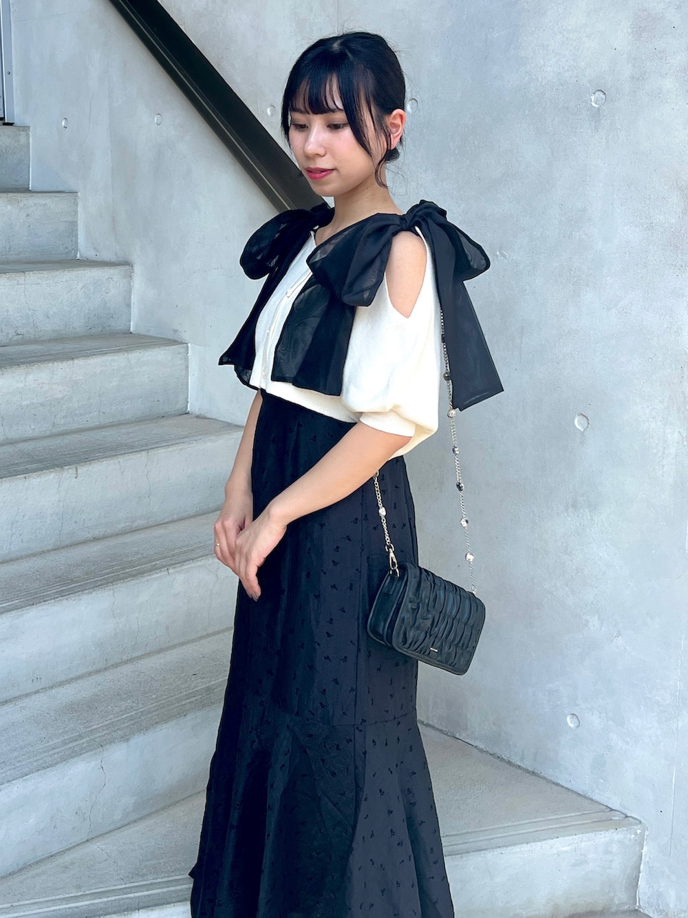 ホワイト系のワンピース、ブラック系のショルダーバッグを着用したレディースの夏コーディネートの2枚目の写真