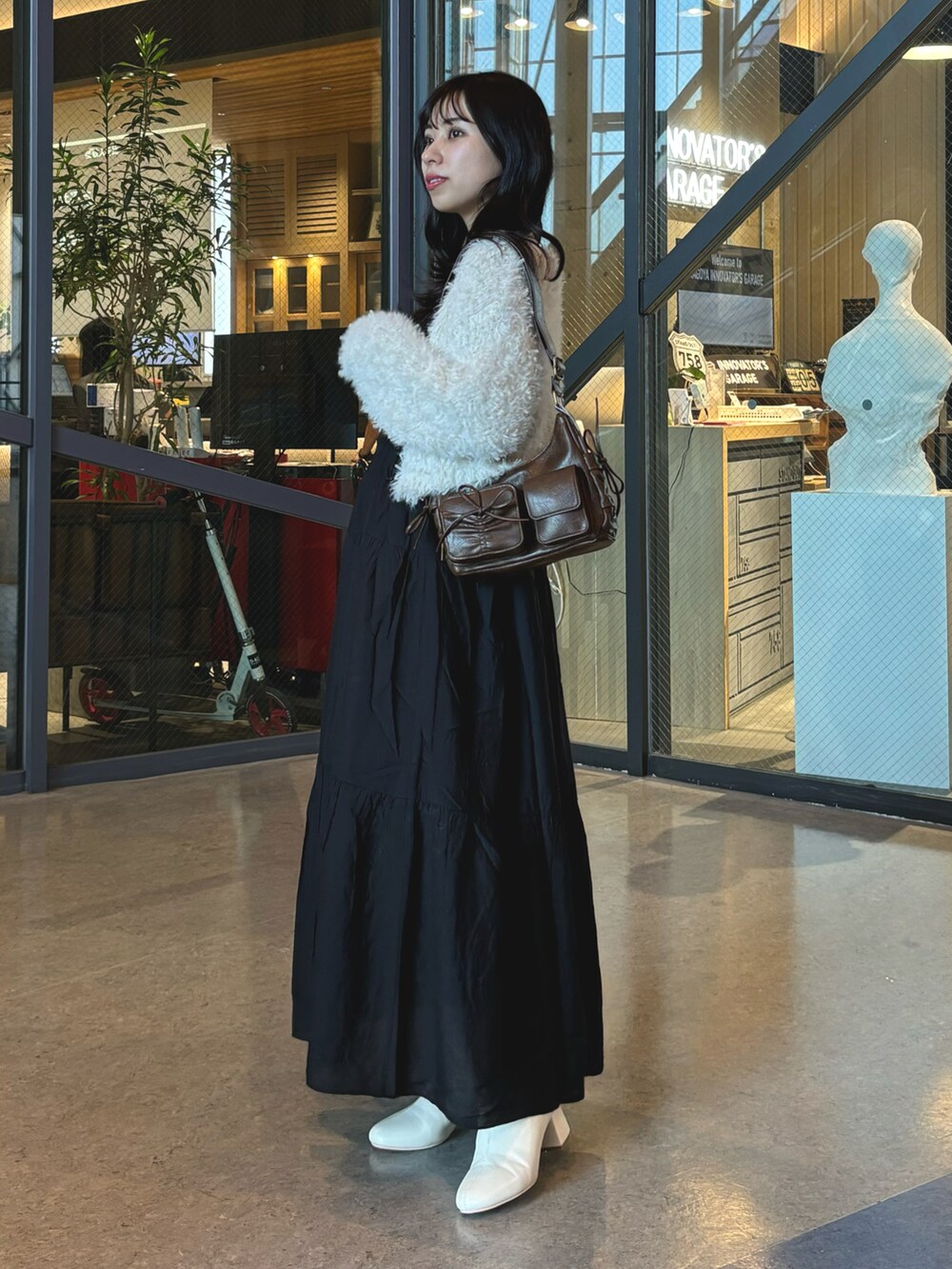 ブラック系のワンピース、ブラック系のショルダーバッグ、ホワイト系のカーディガン/ボレロを着用したレディースの秋コーディネートの2枚目の写真