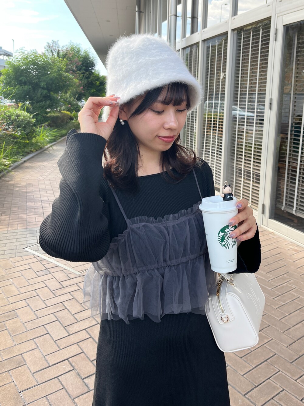 ブラック系のワンピース、ホワイト系のショルダーバッグ、ホワイト系のハットを着用したレディースの秋コーディネートの2枚目の写真