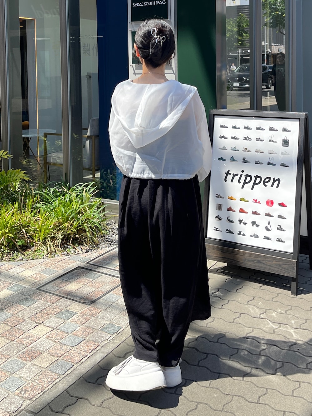 ブラック系のワンピース、ホワイト系のマウンテンパーカー、ホワイト系のスニーカーを着用したレディースの春コーディネートの2枚目の写真