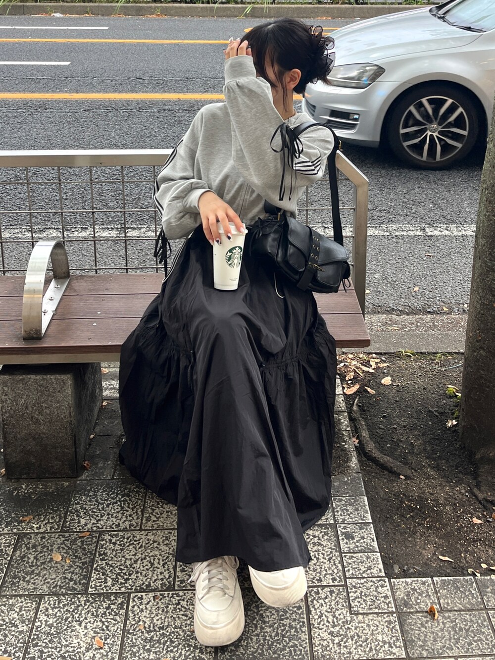 グレー系のパーカー、ブラック系のショルダーバッグ、ホワイト系のスニーカーを着用したレディースの夏コーディネートの2枚目の写真