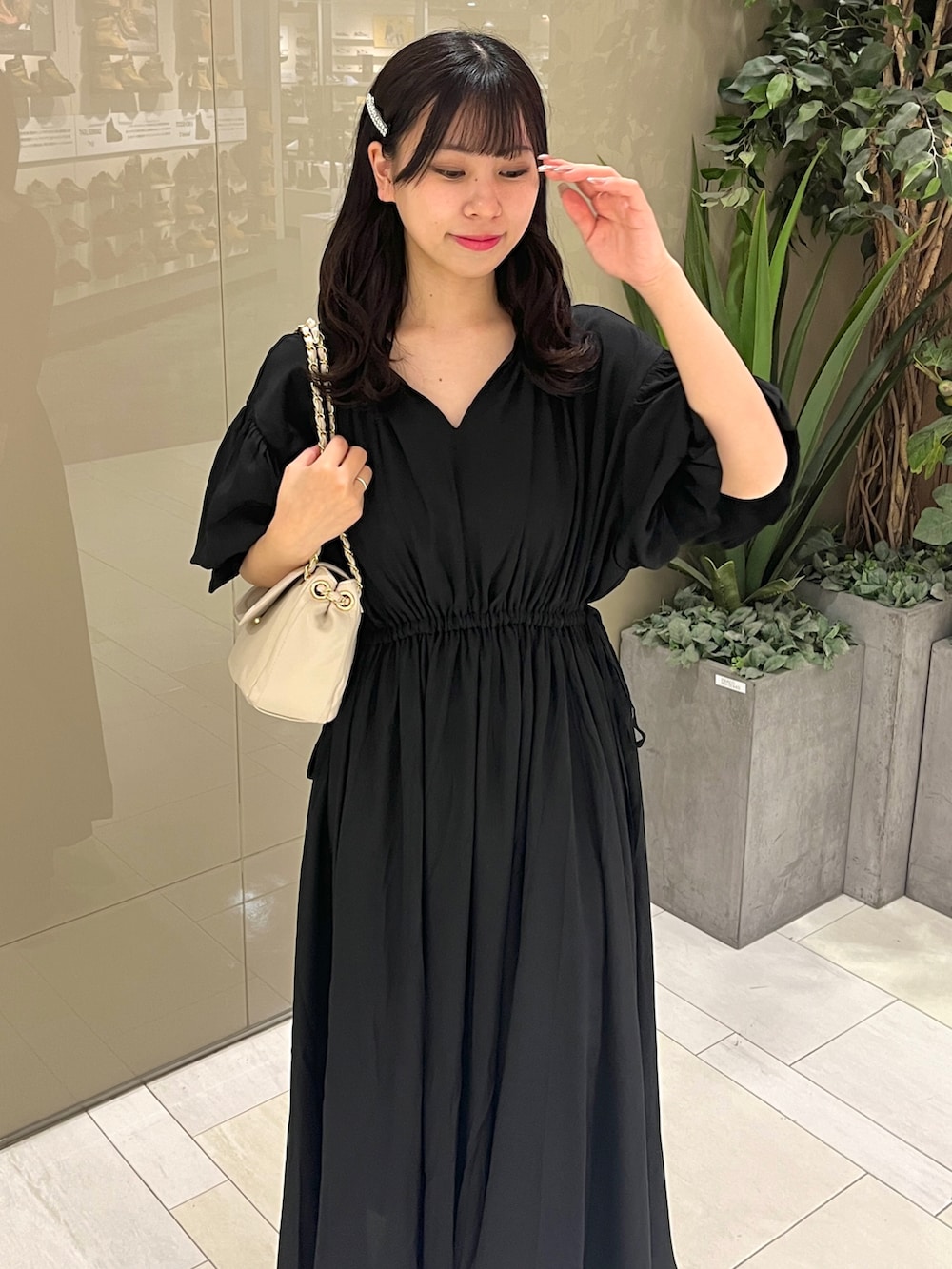 ブラック系のワンピース、ブラック系のブーツ、ベージュ系のショルダーバッグを着用したレディースの春コーディネートの2枚目の写真