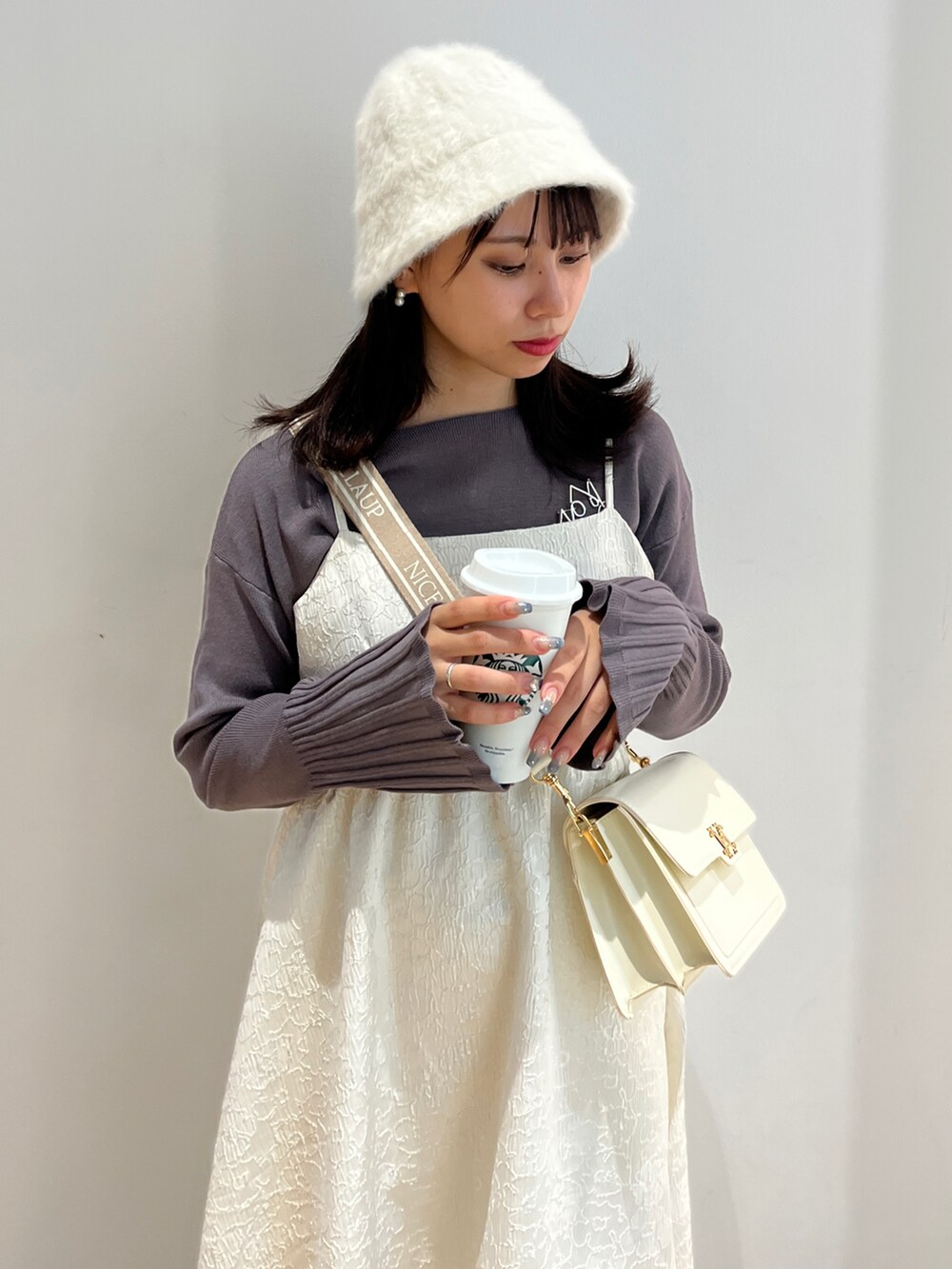 ホワイト系のワンピース、グレー系のニット/セーター、ホワイト系のスニーカーを着用したレディースの秋コーディネートの2枚目の写真