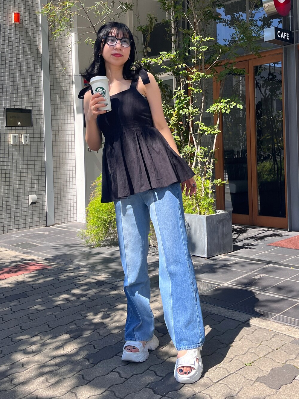 ブラック系のトップス、その他のデニムパンツ、ホワイト系のサンダルを着用したレディースの夏コーディネートの2枚目の写真