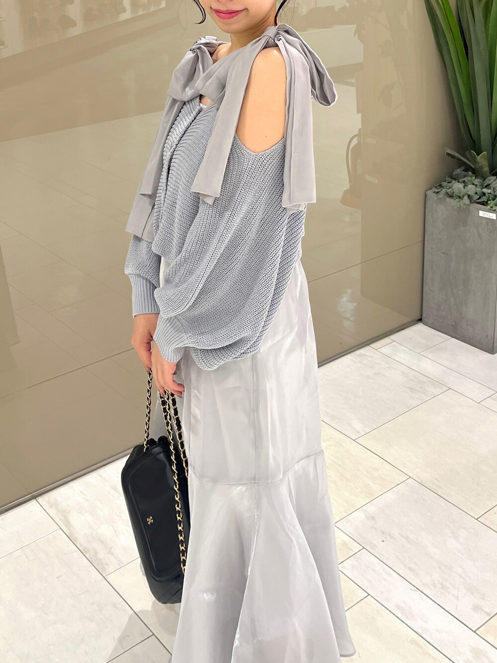 ブルー系のワンピース、ブラック系のブーツ、ブラック系のショルダーバッグを着用したレディースの春コーディネートの2枚目の写真