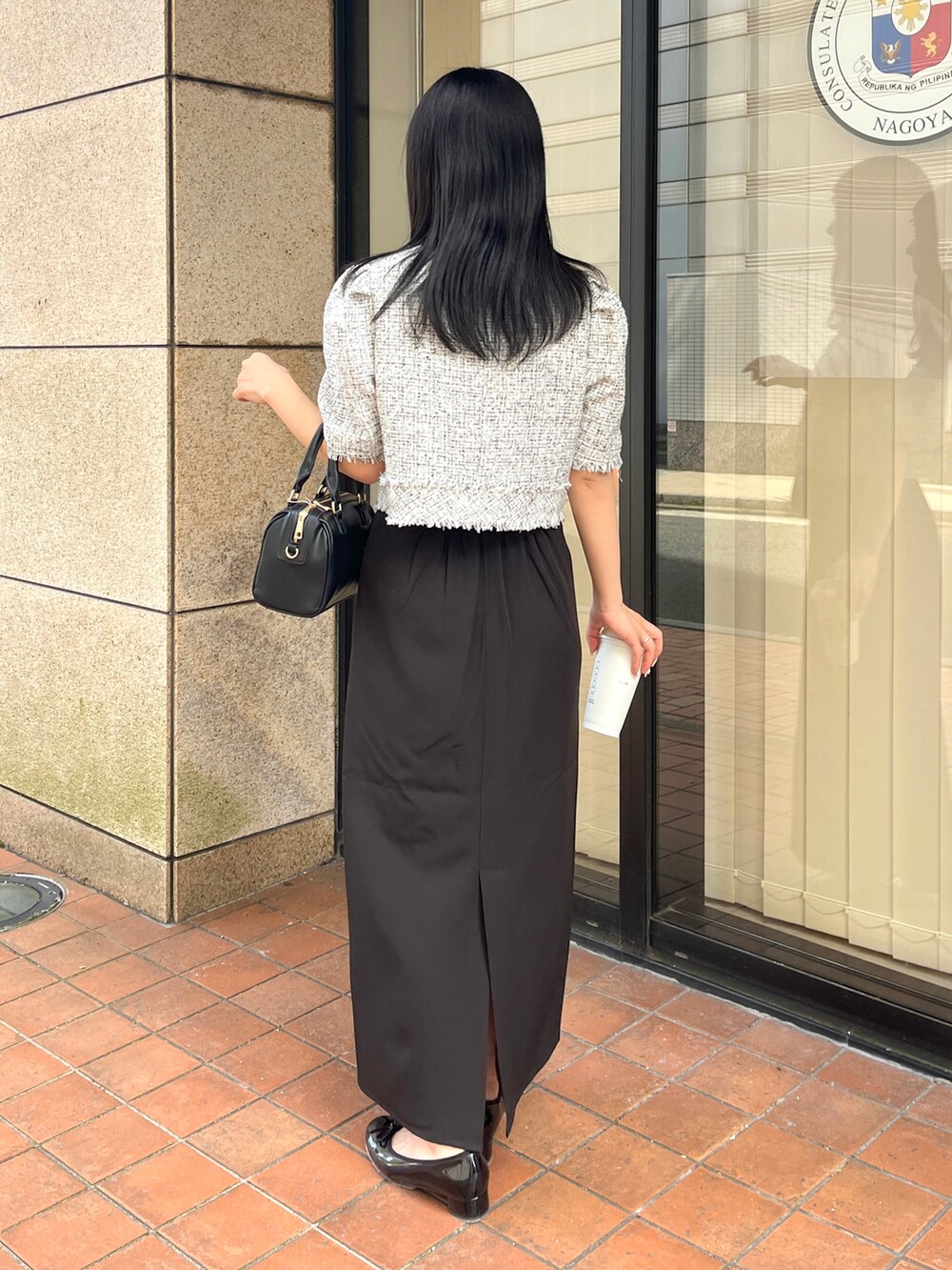 ブラック系のスカート、ブラック系のノーカラージャケット、ブラック系のショルダーバッグを着用したレディースの春コーディネートの2枚目の写真