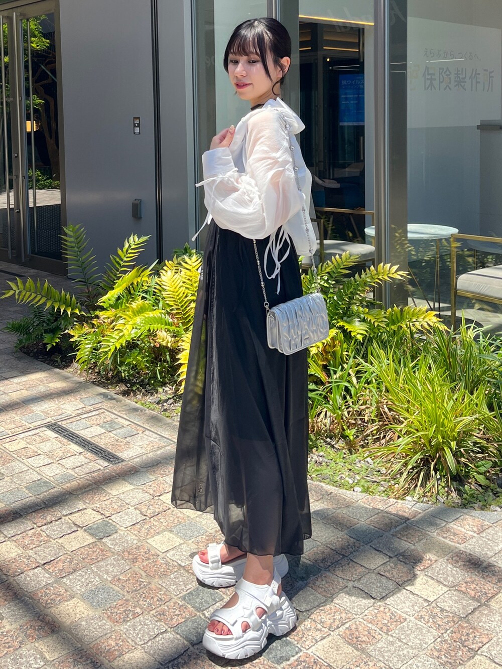 ブラック系のワンピース/ドレス、ホワイト系のシューズ、ホワイト系のショルダーバッグを着用したレディースの春コーディネートの2枚目の写真