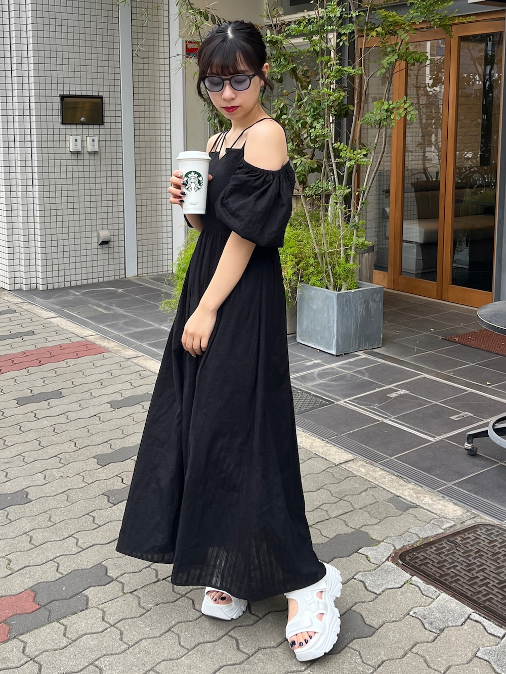 ブラック系のワンピース、ホワイト系のサンダルを着用したレディースの夏コーディネートの2枚目の写真