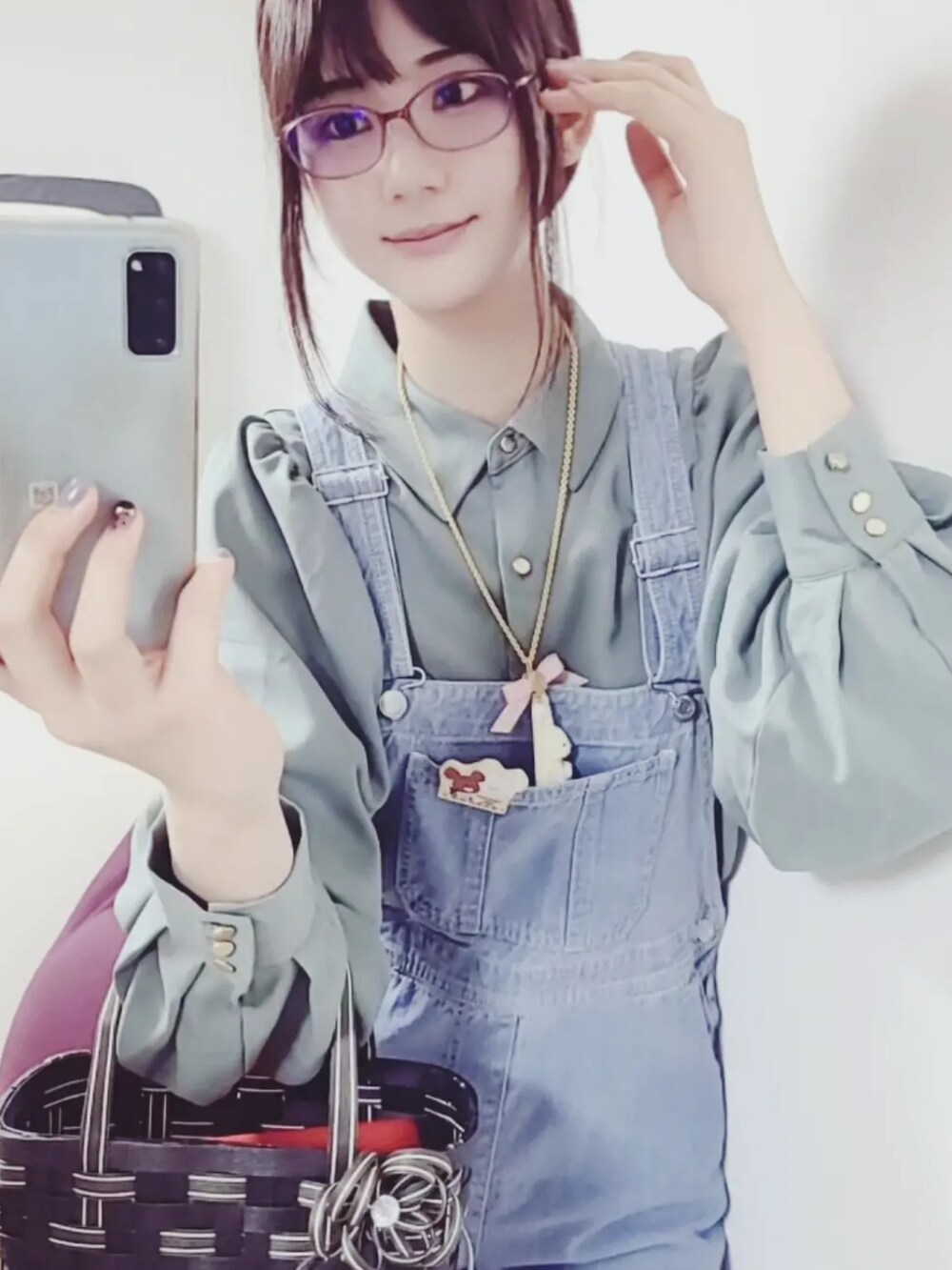 ブルー系のサロペット/オーバーオール、グリーン系のシャツ/ブラウス、ホワイト系のスリッポンを着用したレディースの春コーディネートの2枚目の写真