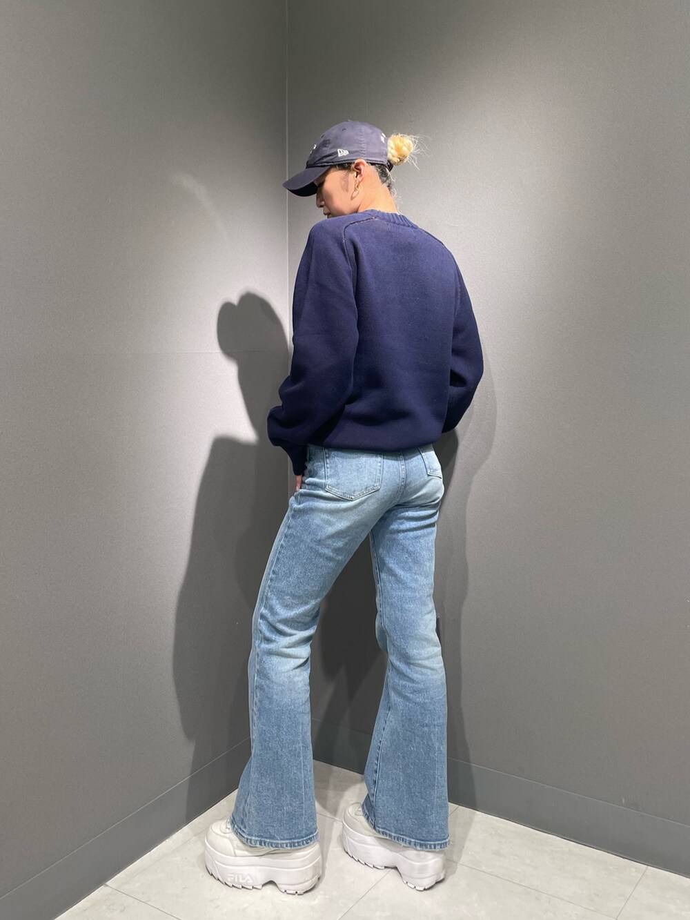 ブルー系のデニムパンツ、ブルー系のニット/セーター、ブルー系のキャップを着用したレディースの秋コーディネートの2枚目の写真