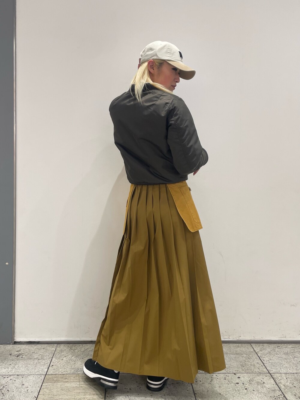 ブラウン系のMA-1、ブラック系のスニーカー、イエロー系のスカートを着用したレディースの冬コーディネートの2枚目の写真