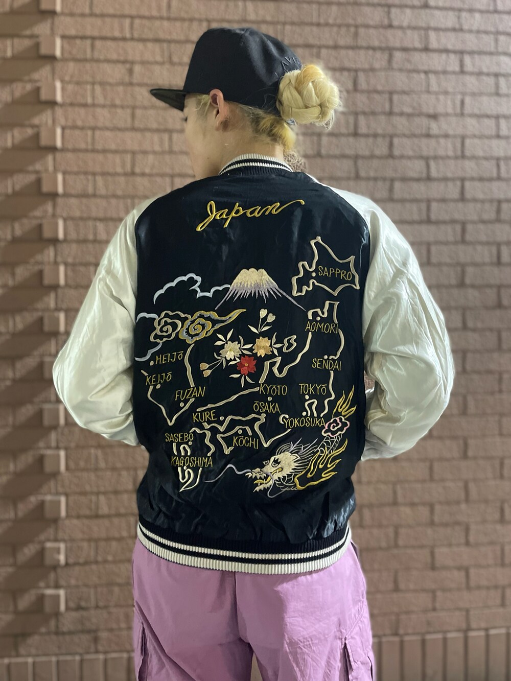 パープル系のカーゴパンツ、ブルー系のスカジャン、ブラック系のキャップを着用したレディースの春コーディネートの4枚目の写真