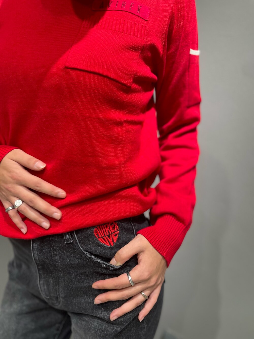 ブラック系のデニムパンツ、レッド系のニット/セーター、シルバー系のリングを着用したレディースの秋コーディネートの3枚目の写真