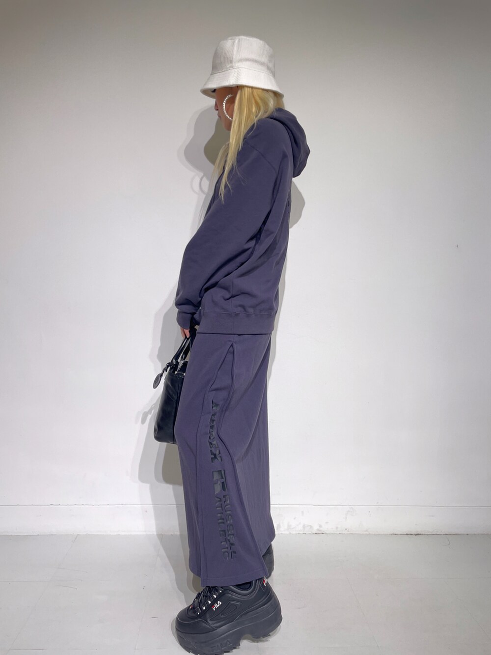 ブラック系のスカート、ブラック系のパーカー、ブラック系のトートバッグを着用したレディースの秋コーディネートの3枚目の写真