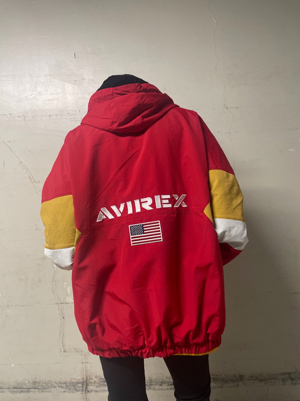 レッド系のナイロンジャケット、イエロー系のスウェット、ブラック系のその他パンツを着用したレディースの冬コーディネートの2枚目の写真