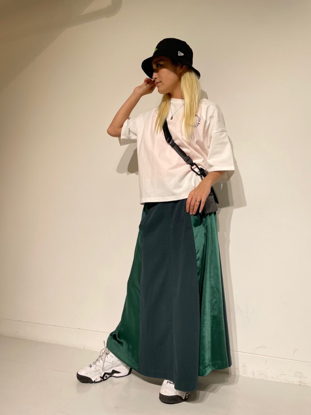 グリーン系のスカート、ホワイト系のTシャツ/カットソー、ブラック系のショルダーバッグを着用したレディースの春コーディネートの2枚目の写真