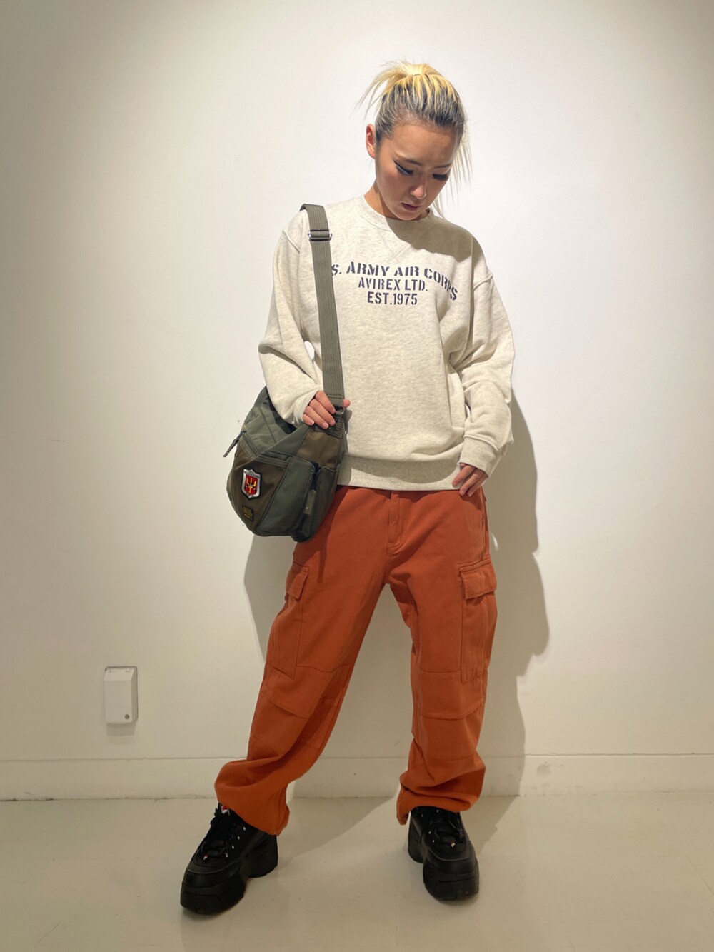 ベージュ系のスウェット、レッド系のカーゴパンツ、グリーン系のショルダーバッグを着用したレディースの冬コーディネートの2枚目の写真