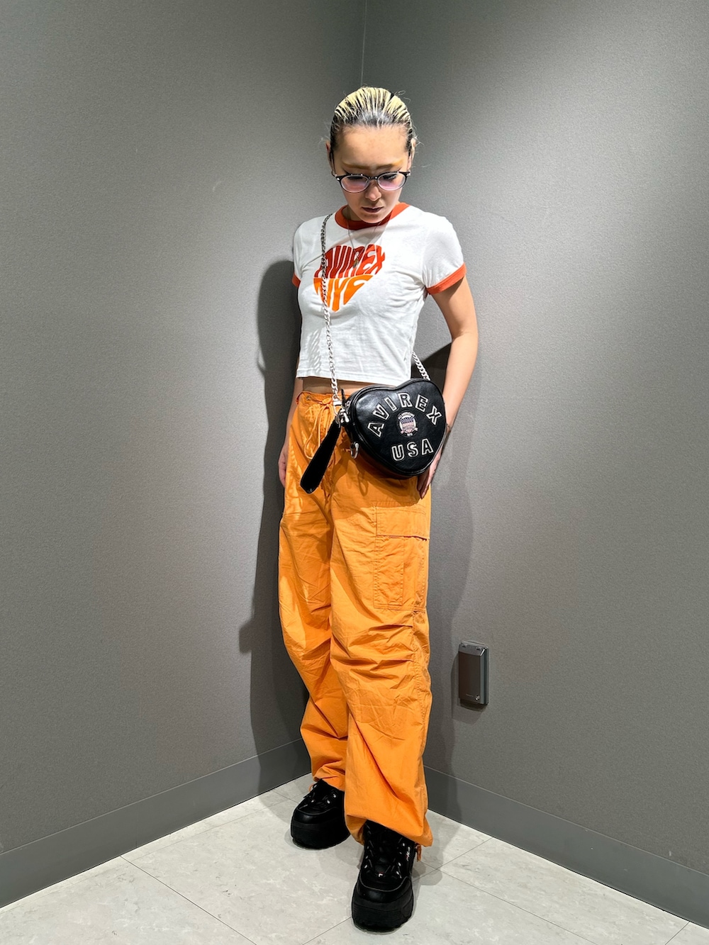 ホワイト系のTシャツ/カットソー、オレンジ系のカーゴパンツ、ブラック系のショルダーバッグを着用したレディースの春コーディネートの2枚目の写真