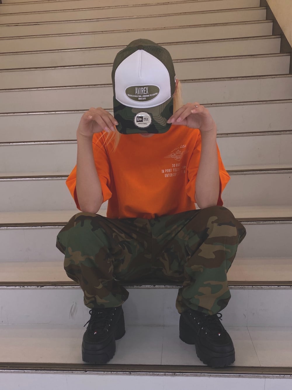 オレンジ系のTシャツ/カットソー、ベージュ系のキャップを着用したレディースの夏コーディネートの3枚目の写真